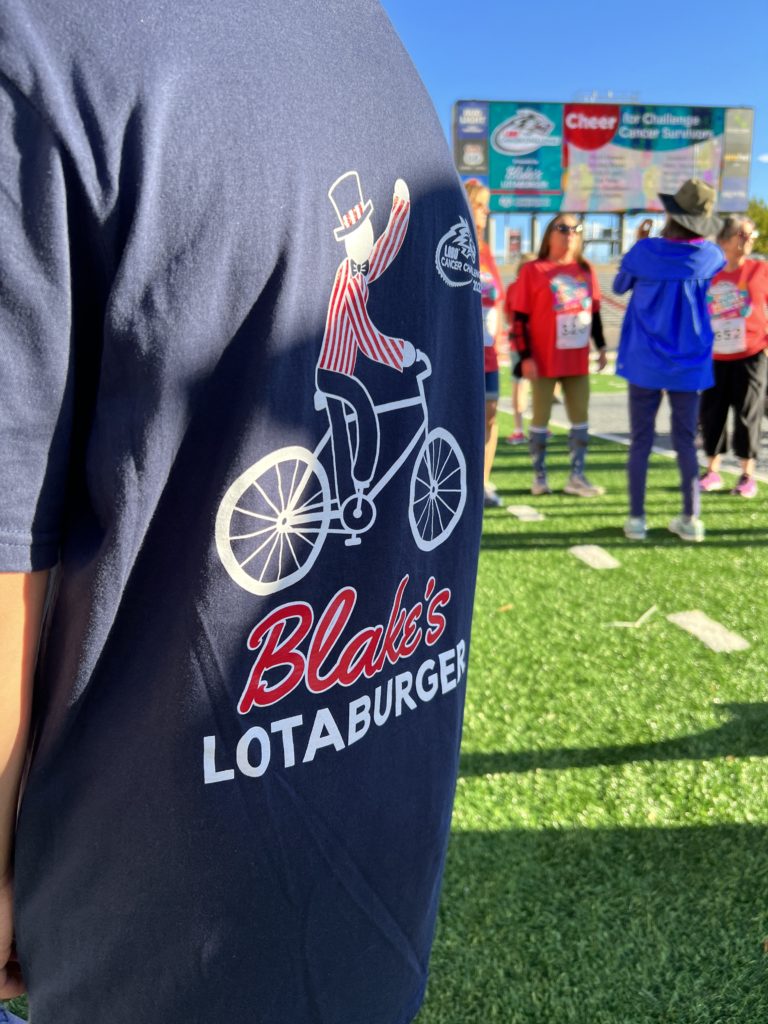 backside of a Blake's Lotaburger t-shirt with team in the background