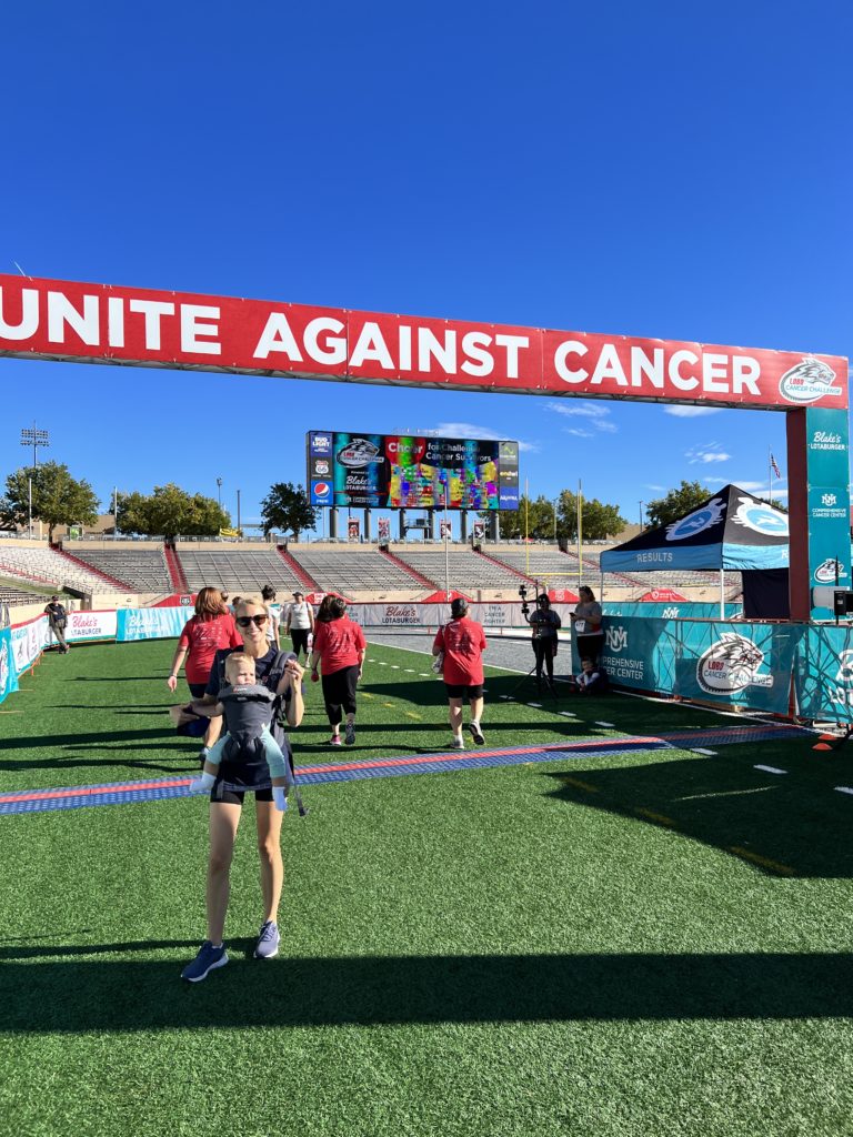 Team members of Blake's crossing a finish line while one poses for camera with baby