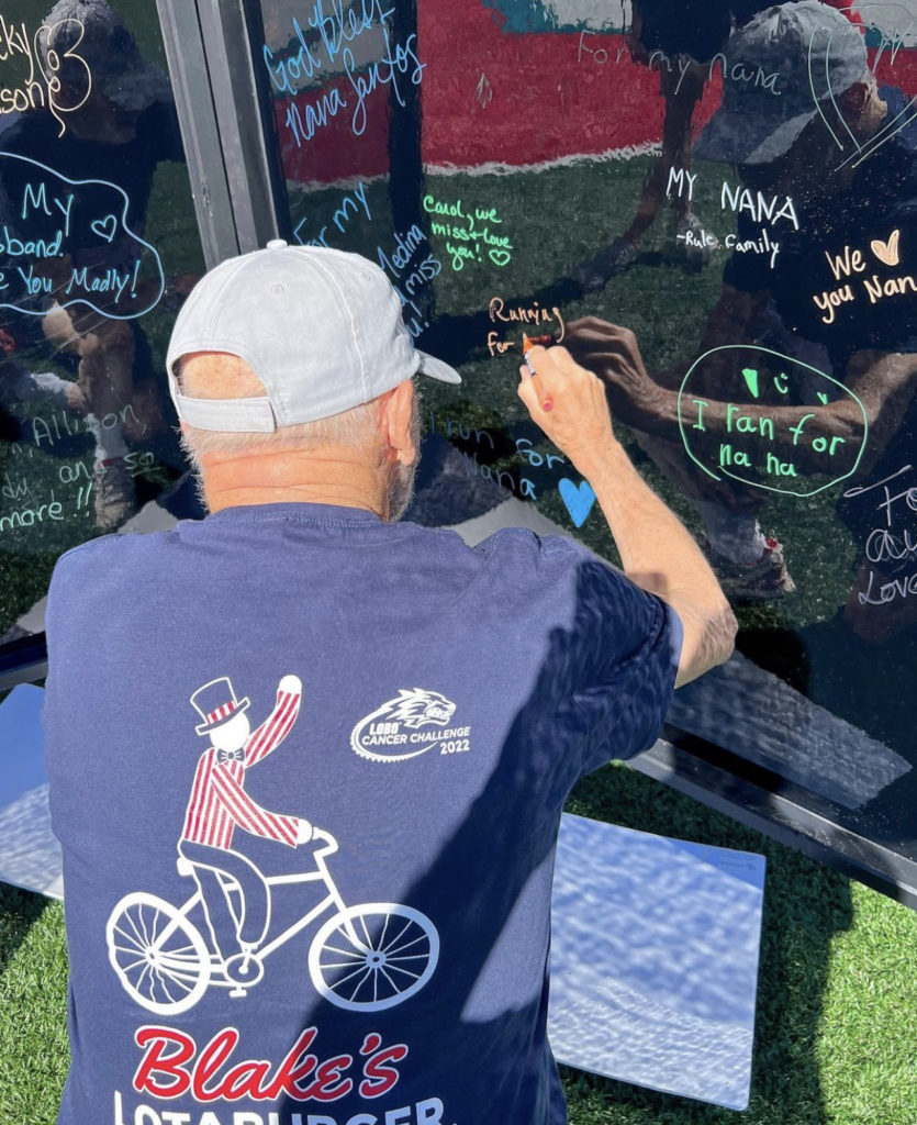 Blake's team member signing a signiture wall weating a blake's t-shirt