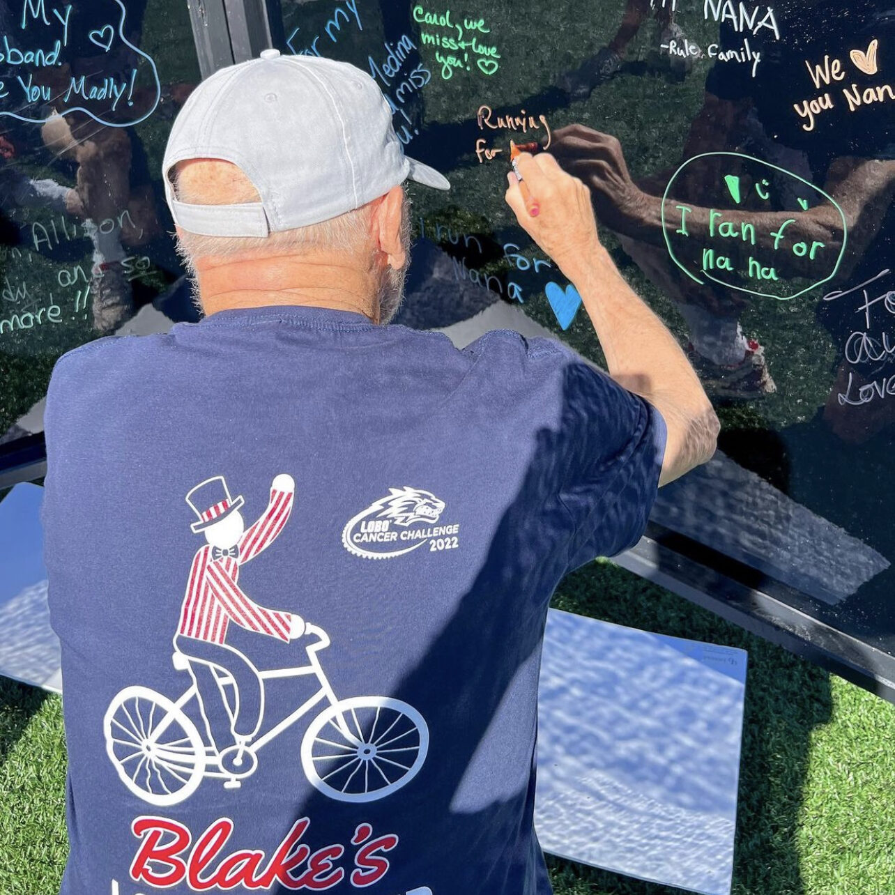 Blake's team member signing a signiture wall weating a blake's t-shirt