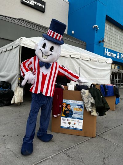 Blake's Mascot standing in front of a box filled with coat donations.
