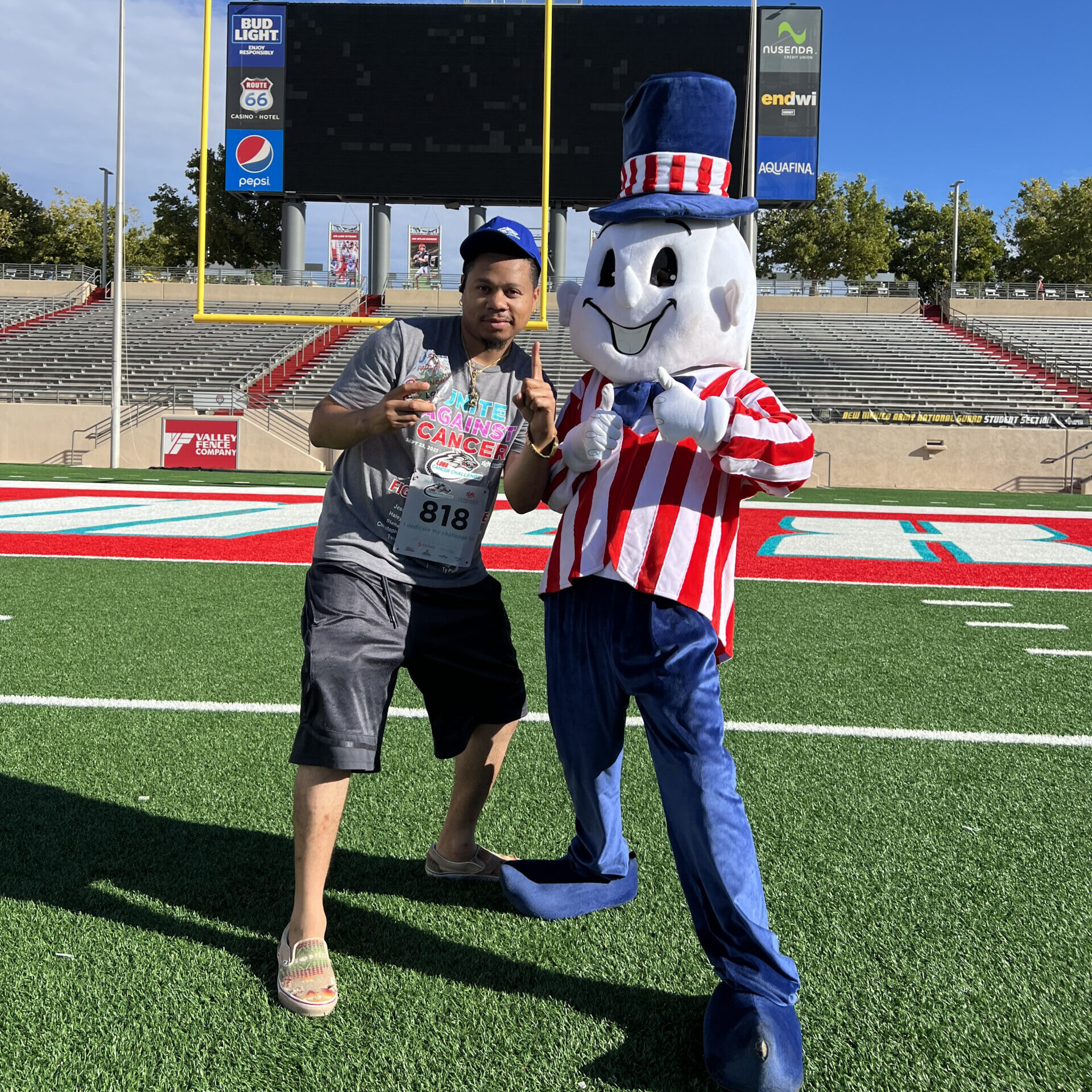 Guy getting his photo taken with Blake's Mascot in front of a goal post