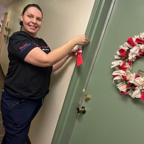 Woman hanging a stocking on a doorway with a wreath on it