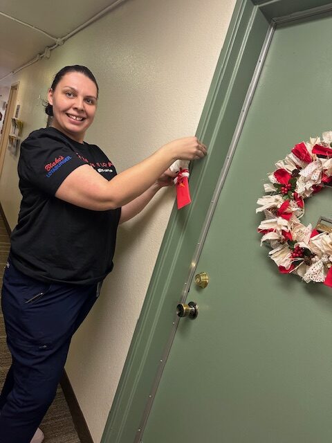 Woman hanging a stocking on a doorway with a wreath on it