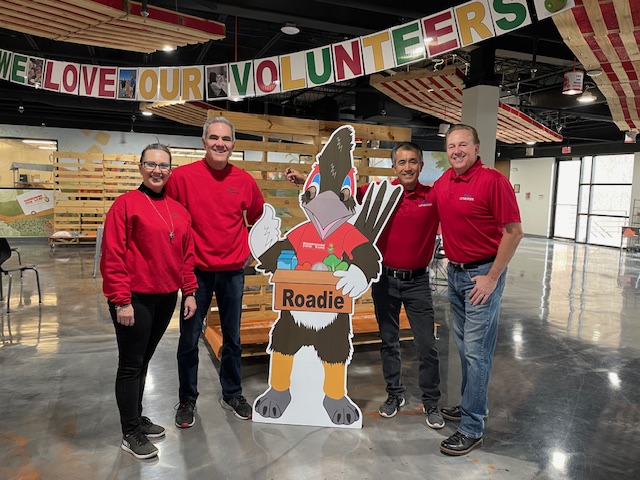 Blakes Team standing in front of a cardboard cutout of the roadrunner food bank mascot
