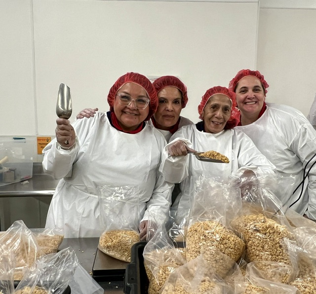 Blake's team members packing food at Road Runner Food Bank with hairnets and coveralls.