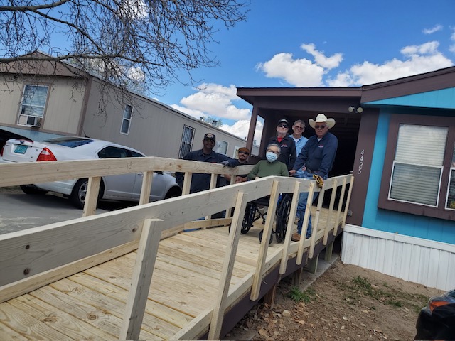 Blake's team standing over the completed ramp with the resident of the home