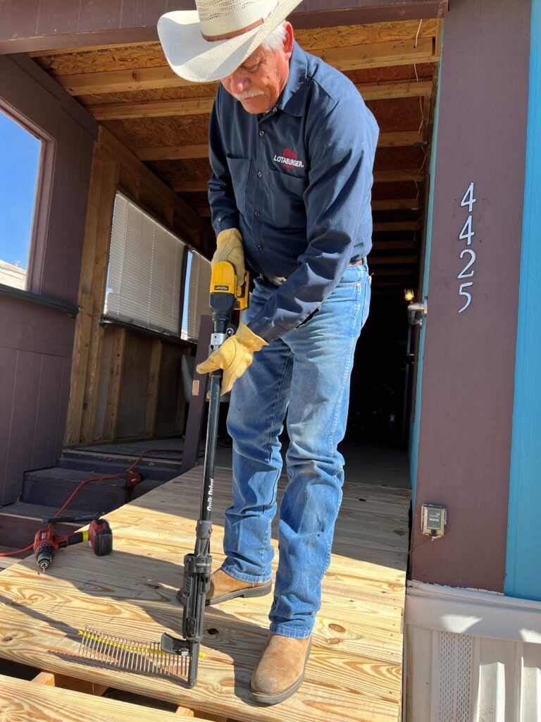 Blake's team member using a long nail gun to attach boards