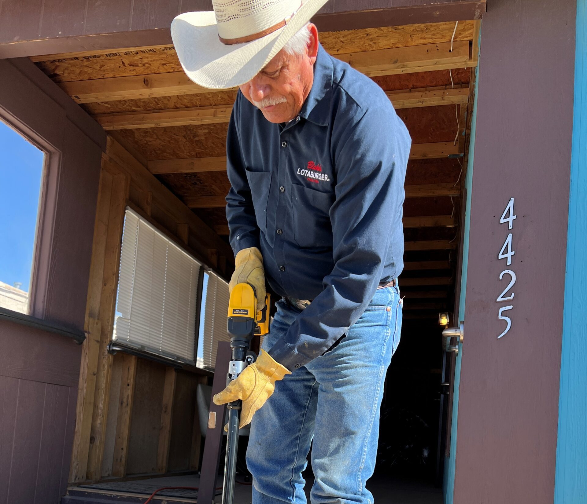 Blake's team member using a long nail gun to attach boards
