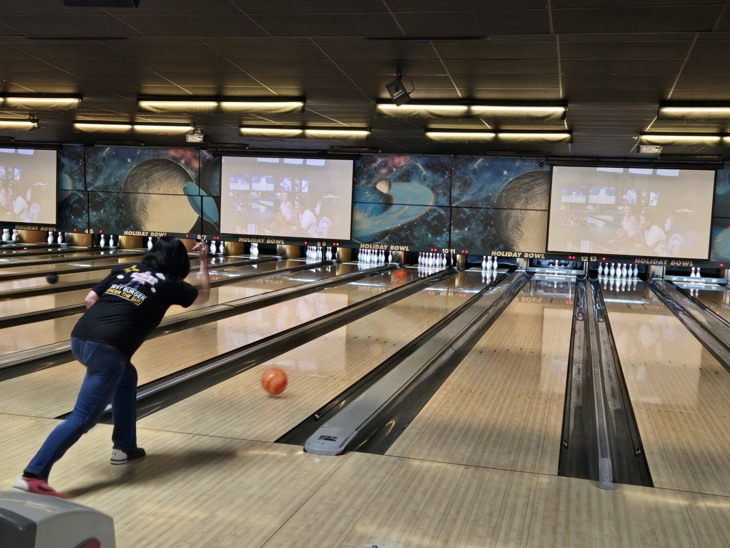 Image of a woman rolling a bowling ball down an alley