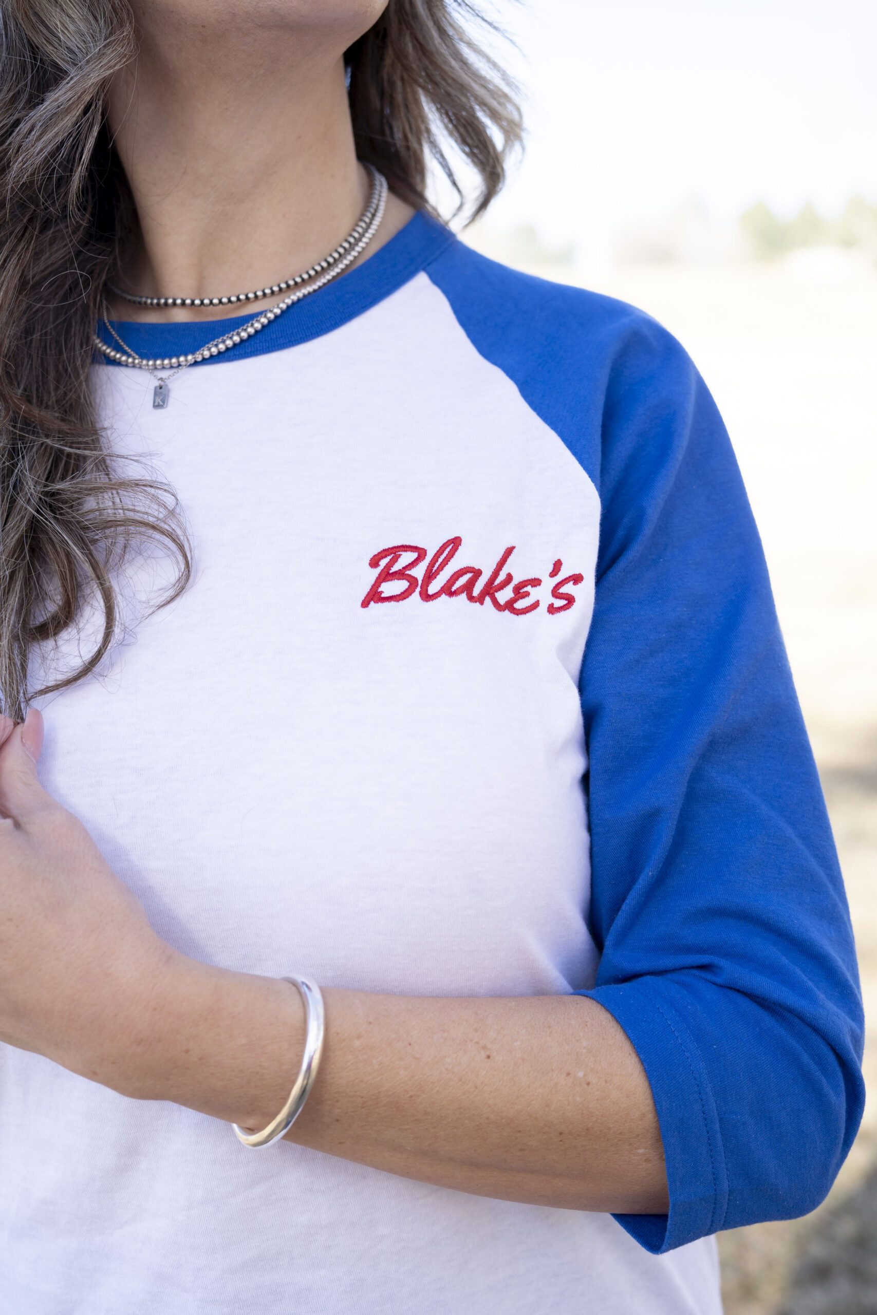 a person wearing a baseball cut t-shirt with the word Blake's embroidered on it in red