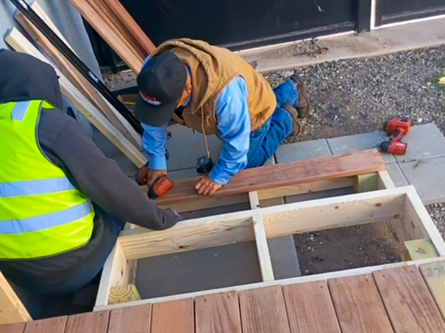 two team members kneeling down building a new ramp for a home